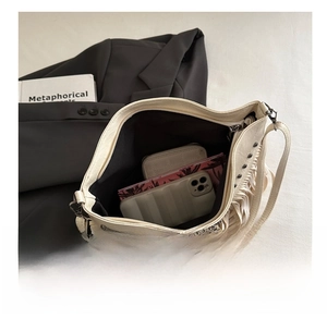 Detail view of spacious interior of cream tassel shoulder bag with metal studs