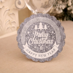 Detailed close-up of light gray felt Christmas coaster with white printed tree and greetings
