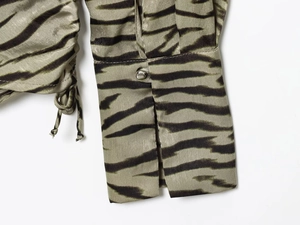 Detailaufnahme der olivgrünen Satin-Ärmel mit Tiermuster, Knopf und Kordelzug