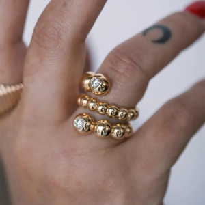 Bague en acier inoxydable doré avec deux pierres blanches portée sur le doigt d'un mannequin