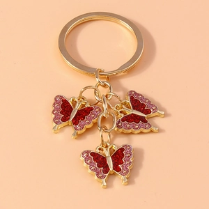 Close-up of golden keychain featuring three red glitter enamel butterfly pendants on a ring
