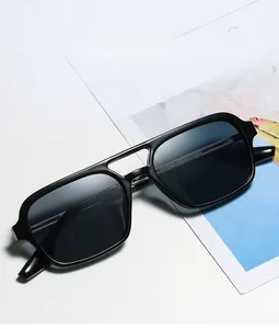 Detailed view of black square double-bridge sunglasses on a minimalist white surface