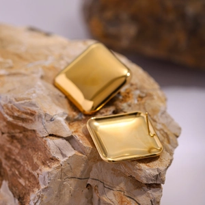 Detailed view of polished 18k gold plated square stud earrings on natural stone