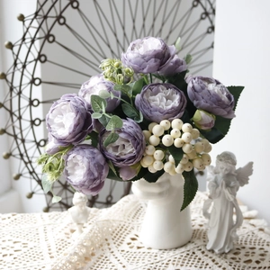 Purple faux peonies and white berries in a creative ceramic face-shaped vase