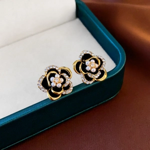 Détail de boucles d'oreilles fleur vintage en émail noir, perles et zircons sur écrin