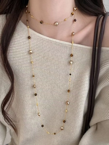 Close-up of double-layer vintage tiger eye and pearl necklace on beige sweater