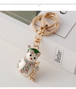 Detail of a skiing snowman keychain with white enamel and sparkling rhinestones