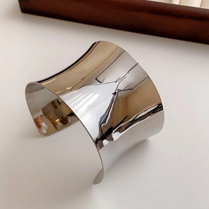Detailed close-up of a silver irregular concave open bangle with a polished mirror finish