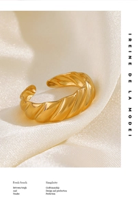 Macro detail of golden croissant-style ring on silk fabric with elegant typography