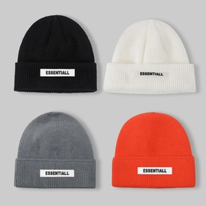 Detailed close-up of knit texture on beanies in black, white, grey, and orange colors