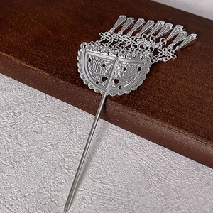 Detail of silver tassel hair pin with crescent hollow carving on a wooden stand