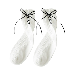 White Lolita calf socks with black ribbon bow and ruffle trim on plain background
