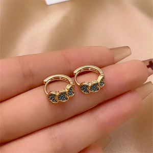 Macro shot of three blue zircon hearts micro-set on golden small hoop earrings
