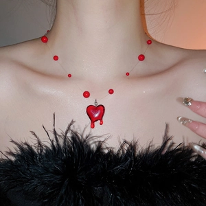 Detail of red melting heart pendant on invisible string necklace worn by a model