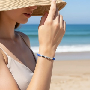 Detail of blue and silver beaded stretch bracelet on wrist with beach background