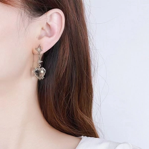 Close-up of model wearing dark red heart zircon earrings with silver star and pleated metal