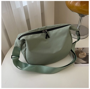 Detail of light bean green nylon dumpling bag with dual metal zippers and adjustable strap