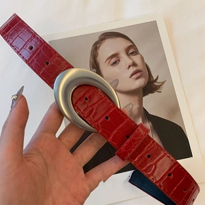 Vue détaillée d'une ceinture en cuir rouge avec motif crocodile et boucle argent