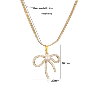 Goldene Schleifen-Halskette mit Perle und Zirkonia-Inlay auf einer flachen Schlangenkette