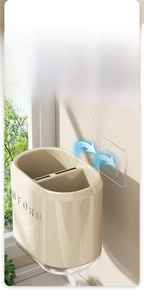 Close-up of wall-mounted kitchen utensil holder showing two compartments and adhesive hook