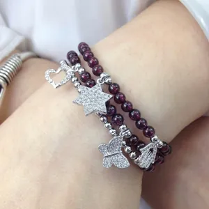 Close-up of triple-layer purple garnet bead bracelet with zircon butterfly and heart charms
