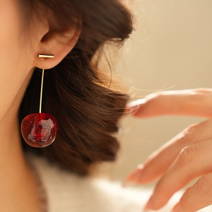 Macro shot of red resin cherry earrings with sparkling glitter and gold stems