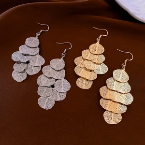 Close-up of gold and silver irregular leaf tassel earrings on brown velvet background