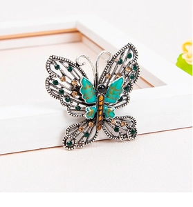 Macro shot of butterfly brooch with green enamel wings and amber rhinestone inlay details