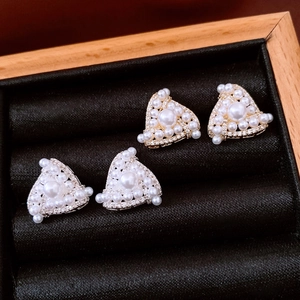 Detailed view of triangle stud earrings with inlaid pearls and sparkling cubic zirconia