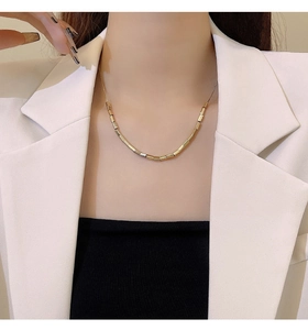 Close-up of a polished golden bamboo style link chain worn on a female model