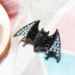 Gothic alloy bat brooch with blue and black rhinestones on a striped fabric background