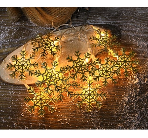 Detail of golden snowflake LED string lights on wood with warm white glow