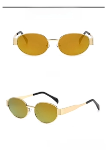 Macro detail of oval metal frame sunglasses in gold with vibrant orange lenses