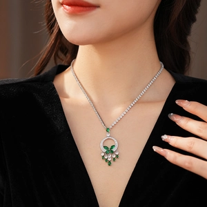 Gros plan d'un collier argenté avec pendentif goutte d'eau vert émeraude porté par un mannequin