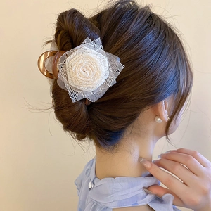 Dettaglio di una molletta per capelli con rosa di pizzo crema su un'acconciatura
