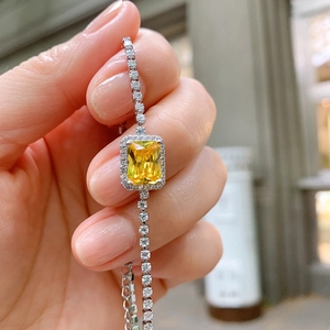 Close-up of a silver bracelet featuring a square yellow gemstone worn on a wrist