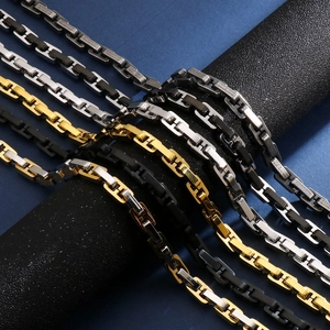 Detail of geometric link chains in gold, silver and black finishes on a textured stand