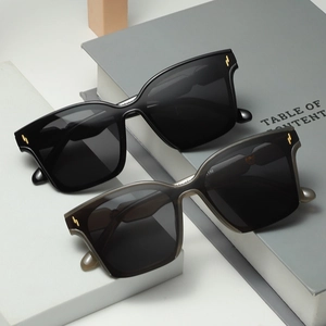 Square oversized sunglasses with black frame and golden metal stripe decor on modern grey props