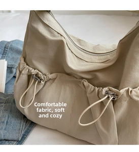 Detail of beige nylon crossbody bag featuring soft pleated texture and drawstring pocket