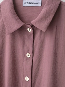 Macro shot of dusty rose shirt collar with crinkled texture and metallic buttons