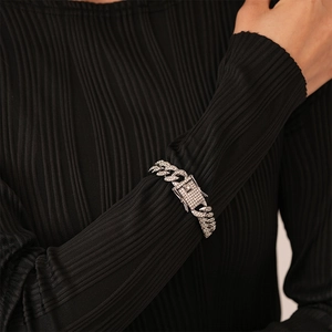Detail of silver iced-out Cuban link bracelet with diamond-encrusted box clasp on wrist