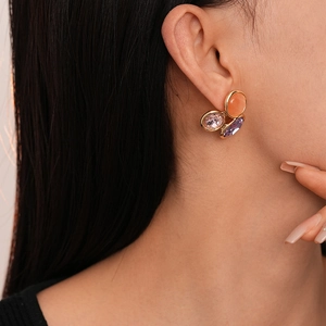 Gros plan de boucles d'oreilles dorées avec pierres œil-de-chat colorées sur le mannequin