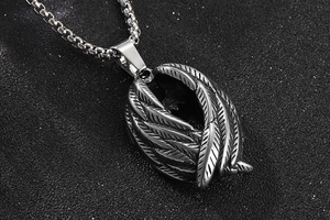 Gros plan détaillé d'un pendentif en forme d'aile d'ange en argent avec texture de plumes