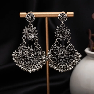 Close-up of vintage silver boho earrings with intricate floral carvings on jewelry stand
