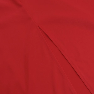 Macro shot of fine stitching and side slit detail on the red satin dress fabric