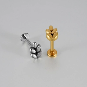 Vue de près de piercings en acier doré et argenté avec motif de feuilles et base plate