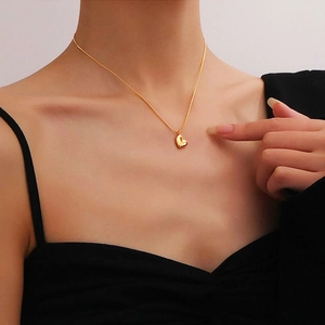 Elegant gold heart pendant necklace on minimalist chain worn by a female model