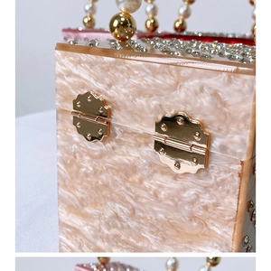 Macro detail of acrylic evening bag featuring pearl handle and rhinestone edging