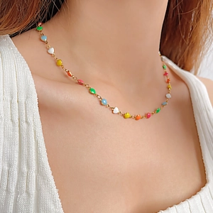 Détail du collier avec pendentifs cœurs arc-en-ciel sur chaîne dorée porté par un mannequin