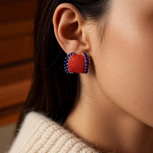 Detailed close-up of a vintage square earring with red and blue crystals on a model